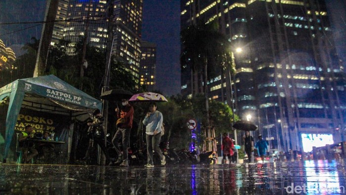 Warga berjalan menggunakan payung saat hujan mengguyur kawasan Jalan Sudirman, Jakarta, Senin (11/11/2024).