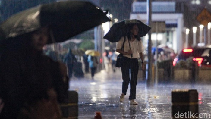 Fenomena La Nina Tingkatkan Curah Hujan di RI Warga berjalan menggunakan payung saat hujan mengguyur kawasan Jalan Sudirman, Jakarta, Senin (11/11/2024).