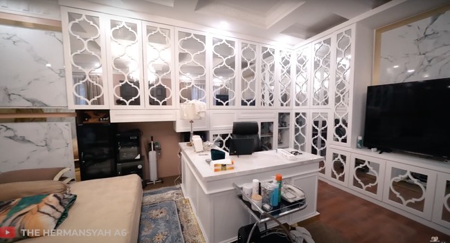 Di salah satu sisi kamar tidur terdapat ruang kerja mini. Meja kerja berwarna putih dipadukan dengan bangku hitam yang senada dengan lemari di kamar tersebut. Foto: YouTube/The Hermansyah A6