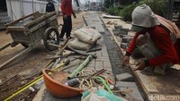 Pekerja tampak tengah memasang paving block.  