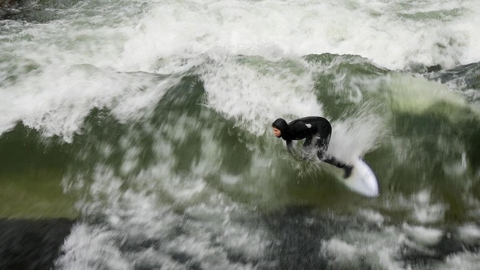 A surfer rides an artificial wave in the river 'Eisbach' at the 'Englischer Garten' (English Garden) downtown in Munich, Germany, Monday, Nov. 11, 2024. (AP Photo/Matthias Schrader)