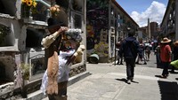 Seseorang berjalan melalui pemakaman selama perayaan Hari Tengkorak atau Natitas, saat orang-orang mengunjungi tengkorak orang yang telah meninggal untuk meminta berkat, kesehatan, dan perlindungan, di La Paz, Bolivia.