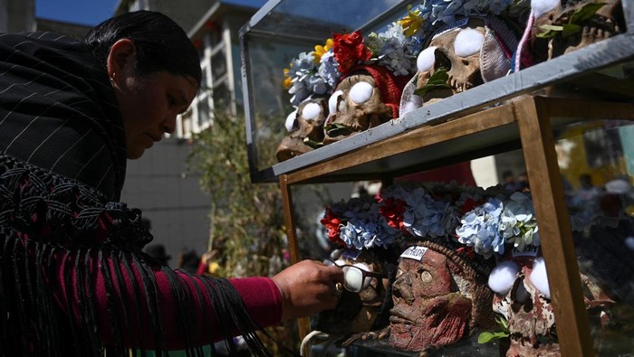 A person stands next to a figure of Santa Muerte during the Day of Skulls or 