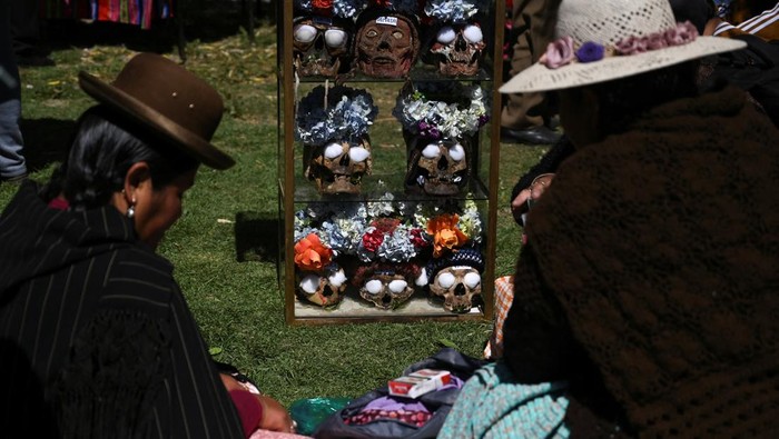 A person stands next to a figure of Santa Muerte during the Day of Skulls or 
