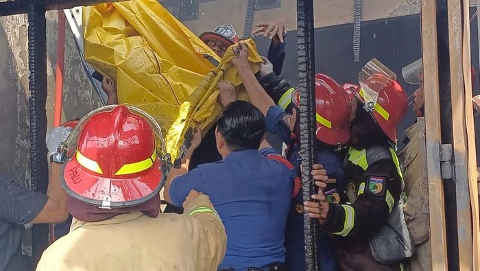 Personel Damkarmat Palu mengevakuasi korban tewas dalam kebakaran ruko.