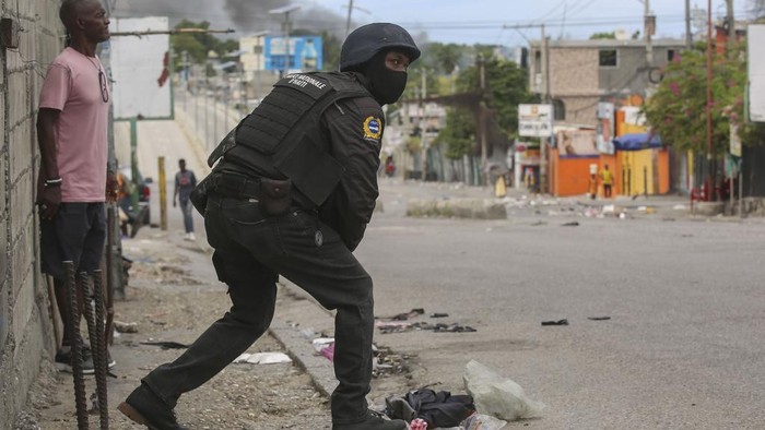 Journalists take cover from the exchange of gunfire between gangs and police in Port-au-Prince, Haiti, Monday, Nov. 11, 2024. (AP Photo/Odelyn Joseph)