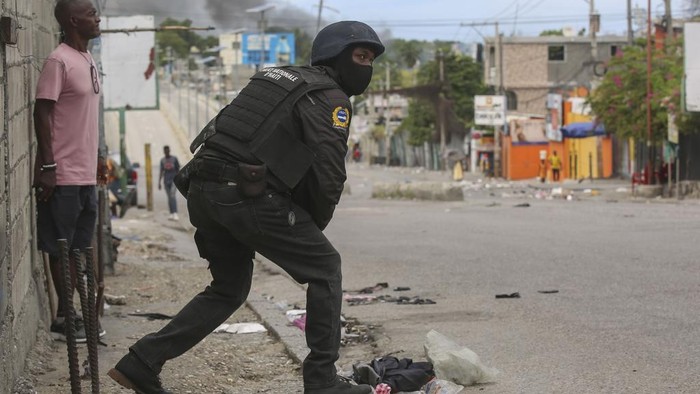 Polisi Haiti Kembali Bentrok dengan Geng Bersenjata Journalists take cover from the exchange of gunfire between gangs and police in Port-au-Prince, Haiti, Monday, Nov. 11, 2024. (AP Photo/Odelyn Joseph)