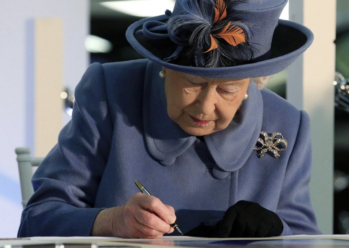 Britains Queen Elizabeth II signs the visitors book to mark her visit to the Siemens Gamesa Renewable Energy wind turbine blade factory in Hull, England, Thursday Nov. 16, 2017.  Queen Elizabeth is visiting Hull the city being named as the UK City of Culture. (Lindsey Parnaby/PA via AP)
