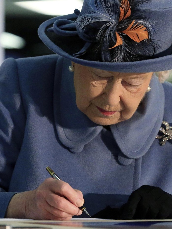 Britains Queen Elizabeth II signs the visitors book to mark her visit to the Siemens Gamesa Renewable Energy wind turbine blade factory in Hull, England, Thursday Nov. 16, 2017.  Queen Elizabeth is visiting Hull the city being named as the UK City of Culture. (Lindsey Parnaby/PA via AP)