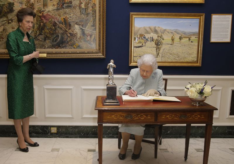 Britain's Queen Elizabeth II signs the visitors book, watched by Princess Anne, following a reception to celebrate the Women's Royal Naval Service 100 project at The Army and Navy Club in London, Thursday, Oct. 12, 2017. (AP Photo/Alastair Grant, Pool)