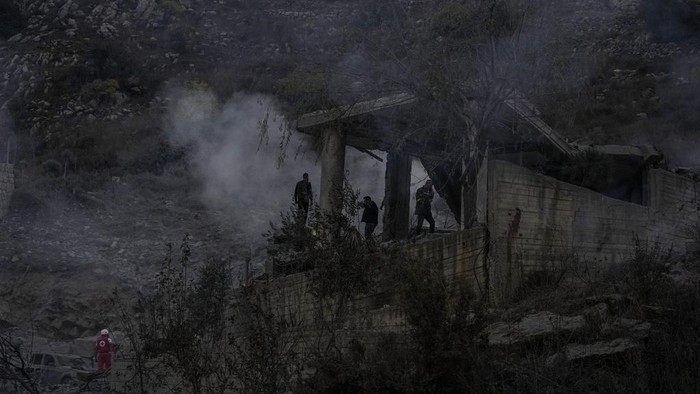Rescue workers search for victims as smoke rises from a destroyed house hit in an Israeli airstrike in Baalchmay village east of Beirut, Lebanon, Tuesday, Nov. 12, 2024. (AP Photo/Hassan Ammar)