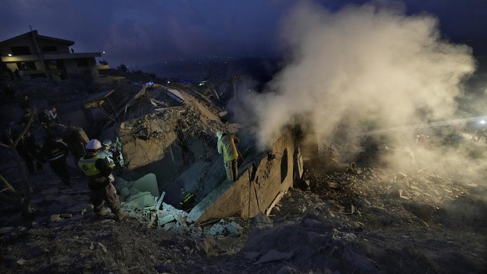 Rescue workers search for victims as smoke rises from a destroyed house hit in an Israeli airstrike in Baalchmay village east of Beirut, Lebanon, Tuesday, Nov. 12, 2024. (AP Photo/Hassan Ammar)