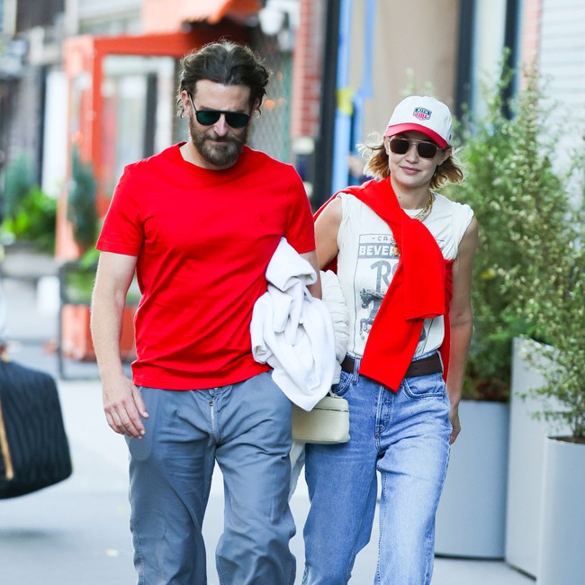 Gigi hadid tampil effortless namun tetap stylish dengan t-shirt putih dan flare jeans. Ibu satu anak ini tampak memakai swater kashmir merah yang dipakai sebagai aksesori dengan dililitkan mengelilingi tubuhnya. Foto: Getty Images