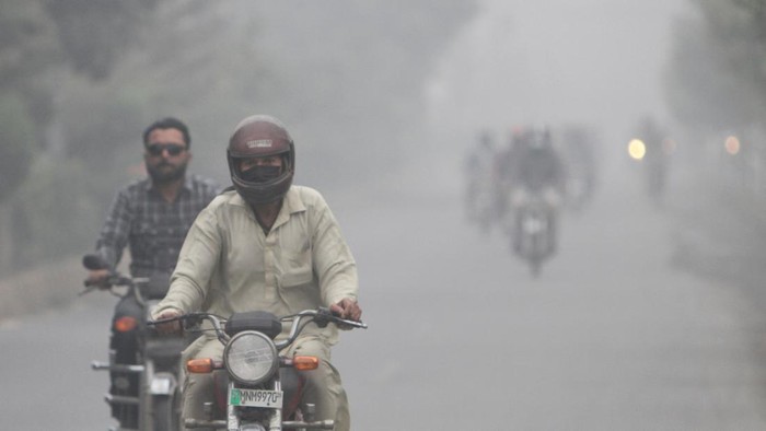 People ride on motorbikes amid smog on a road in Multan, Pakistan November 12, 2024. REUTERS/Quratulain Asim