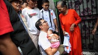 Ridwan Kamil juga menggendong seorang bayi.