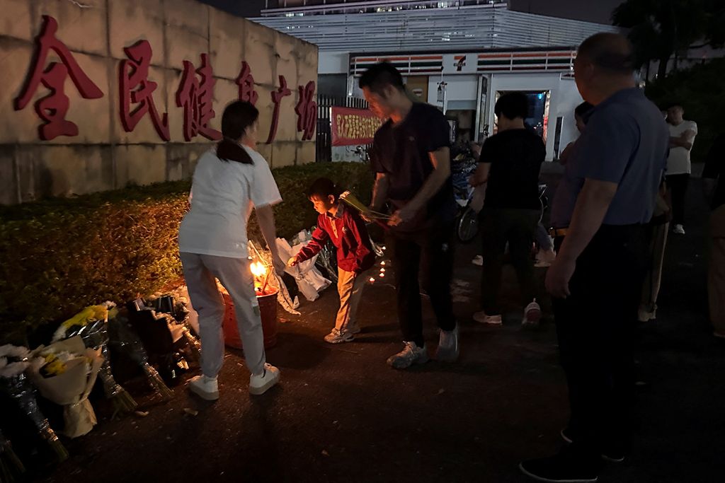 Orang-orang membakar dupa di dekat karangan bunga di luar pusat olahraga tempat serangan tabrak lari mematikan terjadi, di Zhuhai, Guangdong, China, (12/11/2024). (REUTERS/Tingshu Wang)