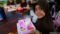 Seorang siswa menunjukkan menu makannya sebelum disantap.