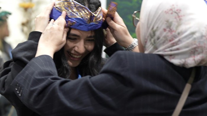 Foto-foto Paviliun Ondonesia COP 29 Salah satu pengunjung mancanegara mengenakan topi khas daerah Bali