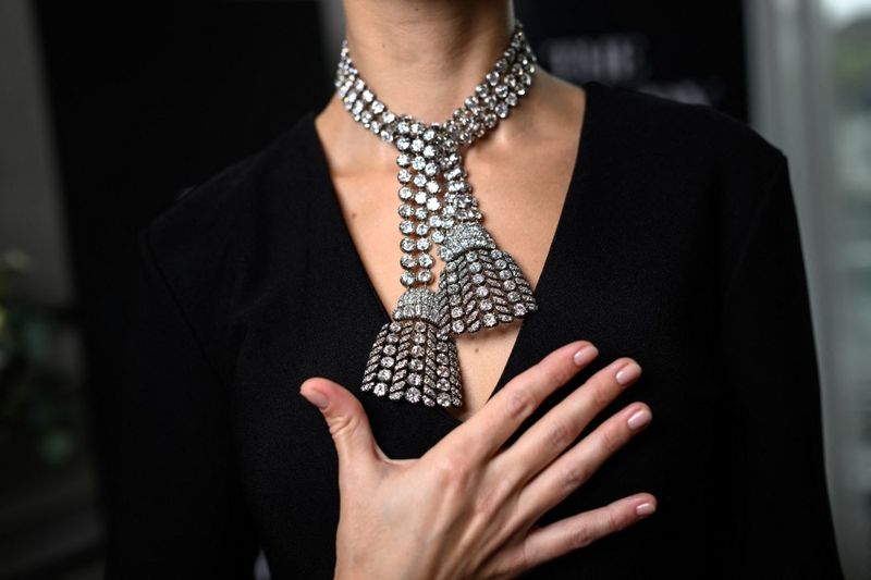 A woman wearing an 18th century diamond jewel necklace composed of three rows of diamonds finished with a diamond tassel at each, weighing approximately 300 carats, poses during a press preview at Sotheby's auction house in Geneva, on November 7, 2024. The mysterious necklace made from around 500 diamonds, some of which are believed to have been taken from a piece that contributed to Marie Antoinette's demise is expected to fetch between $1.8 and $2.5 million when it will go on sale in at Sotheby's in Geneva on 13 November, 2024. (Photo by Fabrice COFFRINI / AFP)