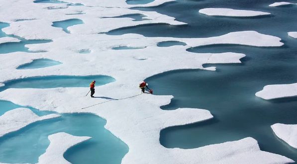 Foto dari udara yang diambil pada 2014 menunjukkan genangan air lelehan es berwarna biru cerah di atas gletser Alaska. Kolam lelehan es serupa semakin umum di seluruh Kutub Utara akibat perubahan iklim dan semakin mempercepat laju hilangnya es di wilayah tersebut.