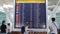 Calon penumpang pesawat melihat informasi jadwal keberangkatan di area Terminal Internasional Bandara Internasional I Gusti Ngurah Rai, Badung, Bali.  