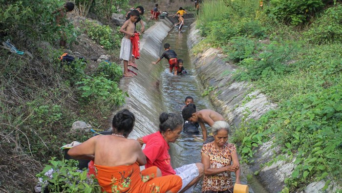 Pengungsi erupsi Lewotobi kekurangan air bersih Pengungsi terdampak erupsi Gunung Lewotobi Laki-laki mandi dan mencuci pakaian dengan menggunakan air parit di dekat posko pengungsian mereka di Desa Kobasoma, Titehena, Flores Timur Nusa Tenggara Timur, Kamis (14/11/2024). Mereka menggunakan air parit untuk kebutuhan MCK karena pasokan air bersih di posko pengungsian menurut mereka kurang memadai. ANTARA FOTO/Mega Tokan/app/tom.