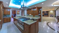 Dapur di rumah Mike Tyson mirip dengan konsep meja bar. Dominan material dari kayu. Terdapat kitchen island dan alat penyedot asap di tengah. Foto: Luxury Homes of Las Vegas via New York Post