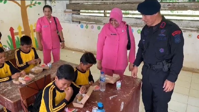 Teks foto: Satbrimob Polda Sumut saat uji coba program makan bergizi di SDN 102092. (Foto: Istimewa)