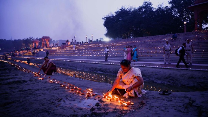 A woman lights a diya during Deepotsav celebrations as the sky is enveloped with smog after Delhi's air pollution turned 