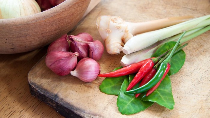Bumbu dapur yang terdiri dari bawang merah, cabe hijau, cabe merah, daun jeruk, serai, dan lengkuas di atas talenan