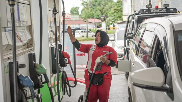 Petugas SPBU sedang melayani konsumen.