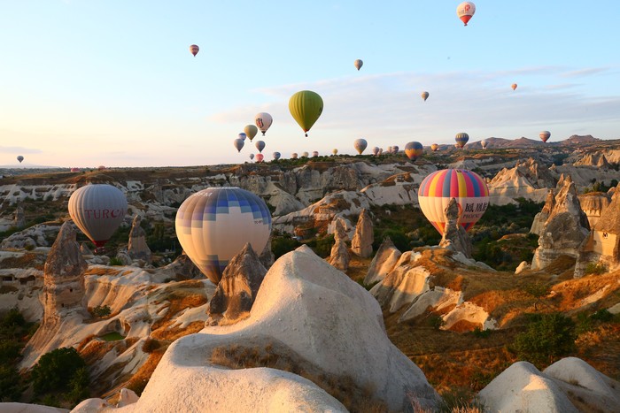 NEVSEHIR, TURKEY - AUGUST 10: Hot air balloons glide over historical Cappadocia region, located in Nevsehir province of Turkey  on August 10, 2021.  A total of 138,225 tourists enjoyed hot air balloon tours in Turkeyâs charming touristic hub Cappadocia between January and July. Cappadocia, listed as one of the UNESCO World Heritage places, is famous with its distinctive plateau, valleys, hills, unique fairy chimney volcanic cones, colorful frescos covering underground cities, boutique hotels, houses carved into rocks, rock churches, chapels, and shelters used by early Christians. (Photo by Behcet Alkan/Anadolu Agency via Getty Images)
