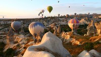 Seperti atraksi yang paling diminati di sana adalah menaiki balon udara yang ketika sampai pada ketinggian tertentu dapat melihat lanskap indah wilayah itu. Kemudian pengunjung juga dapat menyaksikan matahari terbit dan terbenam yang semakin memberikan pengalaman indah kala di Cappadocia. (Behcet Alkan/Anadolu Agency via Getty Images) 