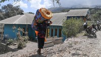 Seorang warga memanggul kasur untuk dibawa ke tempat pengungsian dari rumahnya yang terdampak erupsi Gunung Lewotobi Laki-laki di Desa Klatanlo, Wulanggitang, Kabupaten Flores Timur, NTT, Jumat (15/11/2024). 