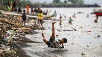 Dua orang anak bermain di pantai sambil berenang antara sampah yang mengapung di laut di Pantai Kalumata Ternate, Maluku Utara, Jumat (15/11/2024). 