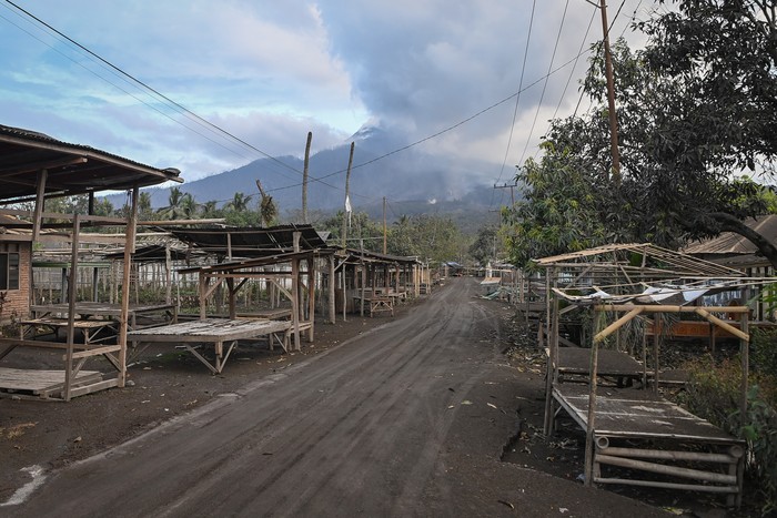 Kondisi Pasar Boru dengan latar belakang erupsi Gunung Lewotobi Laki-laki di Desa Boru, Wulanggitang, Kabupaten Flores Timur, NTT, Minggu (17/11/2024). Pasar yang merupakan pusat perdagangan terbesar dan teramai di Flores Timur bagian barat itu kini ditinggal para pedagangnya yang mengungsi ke sejumlah titik aman pascaerupsi besar Lewotobi hampir dua pekan lalu. ANTARA FOTO/Aditya Pradana Putra/rwa.