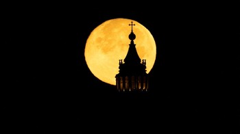 Siluet kubah Santo Petrus terlihat di tengah bulan purnama di Roma, Italia. Namun, secara umum, para astronom cenderung tidak menggunakan istilah-istilah ini, kemungkinan karena asal-usul astrologi istilah supermoon. Astronom punya nama tersendiri untuk supermoon, yakni Bulan syzygy perigee. REUTERS/Remo Casilli