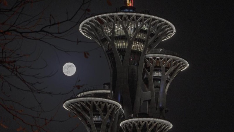 The moon rises over the Olympic Tower in Beijing, Saturday, Nov. 16, 2024. (AP Photo/Ng Han Guan)