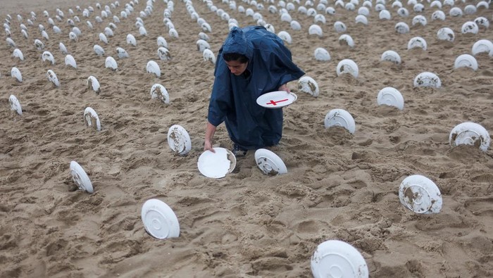 People hold a banner at Copacabana beach, as activists from NGO Rio de Paz display 733 empty plates with red crosses, representing the 733 million people who suffer from hunger worldwide, ahead of the G20 summit in Rio de Janeiro, Brazil November 16, 2024. REUTERS/Pilar Olivares