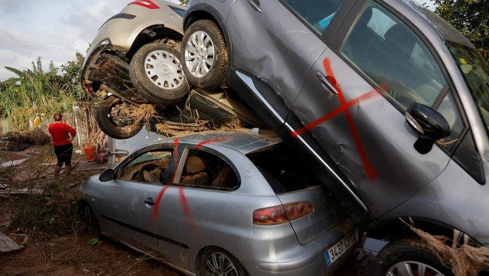 Women walk past a site where cars damaged by heavy rains have piled up in Catarroja, Valencia, Spain, November 16,2024. REUTERS/Eva Manez