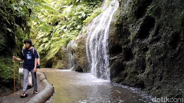 Seorang pengunjung berjalan sebelum menyusuri sungai Tukad Melangit yang menjadi satu-satunya akses menuju Air Terjun Toya Bulan berlokasi di Banjar Kelod, Desa Jehem, Kecamatan Tembuku, Bangli, Bali.