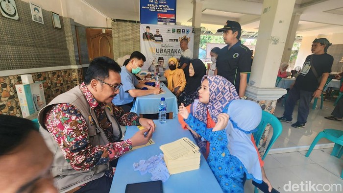 Cabup Sukabumi Asep Japar (kir) saat jadi petugas layanan kesehatan gratis.