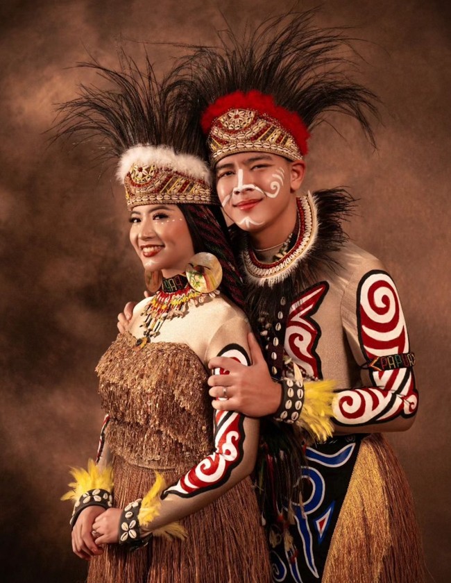 Angela dan Hafiz juga terlihat tampil menjadi pengantin Papua dengan mengenakan baju kurung dan rok rumbai. Penampilannya juga dilengkapi dengan hiasan kepala khas adat Papua. Foto: Instagram/@hafizzyakbar