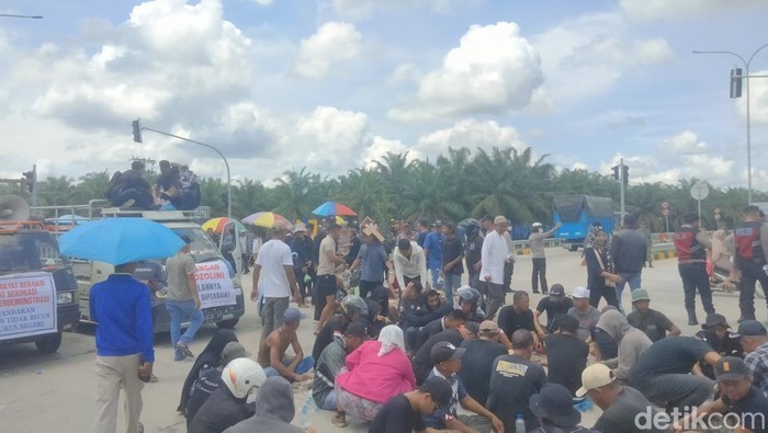 Warga yang berunjuk rasa makan siang di badan jalan dekat pintu tol Kisaran. (Perdana Ramadhan/detikSumut)