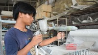Seorang pekerja tengah mengecat miniatur pesawat.  