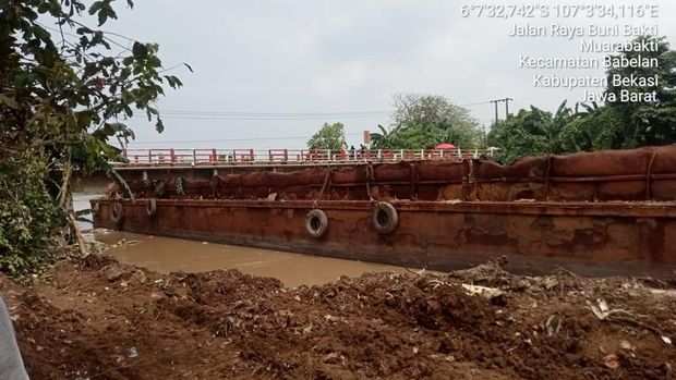 Penampakan kapal tongkang yang hanyut hingga tersangkut di jembatan Kali CBL, Babelan, Kabupaten Bekasi, Selasa (19/11/2024).
