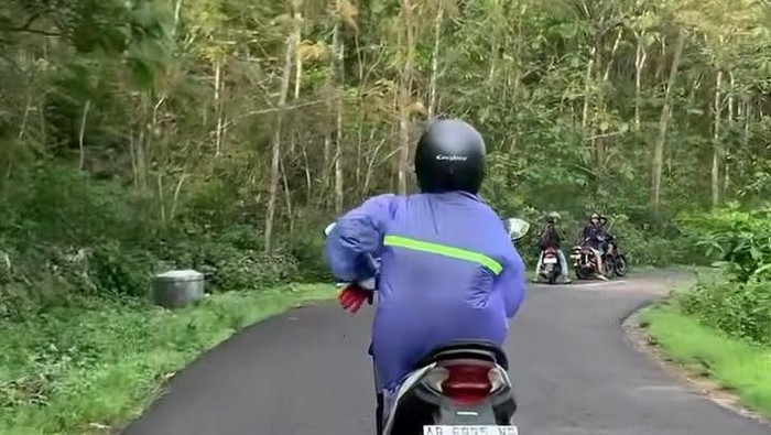 Seorang pemotor yang mengenakan jas hujan meski tidak turun hujan untuk menghindari ulat menempel pada pakaiannya di jalanan Gunungkidul. Foto diunggah Selasa (19/11/2024).