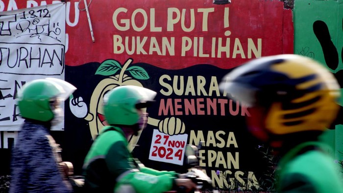 Pengendara melintas di depan mural Pilkada di Depok, Jawa Barat, Selasa (22/10/2024). Mural tersebut sebagai salah satu bentuk sosialisasi sekaligus mendorong masyarakat untuk menggunakan hak suaranya dalam Pilkada 27 November mendatang. ANTARA FOTO/Yulius Satria Wijaya/aww.