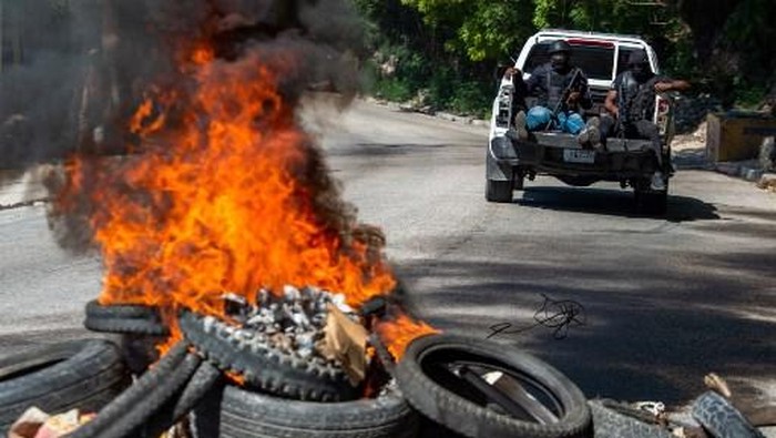 EDITORS NOTE: Graphic content / Members of the Haitian National Police patrol as bodies of alleged gang members burn (in foreground) in Petion-Ville, a suburb of Port-au-Prince, Haiti, on November 19, 2024. Police and civilian self-defense groups killed 28 alleged gang members in the Haitian capital Port-au-Prince in an overnight operation, authorities said Tuesday, as the government seeks to regain some control of the city. (Photo by Clarens SIFFROY / AFP)