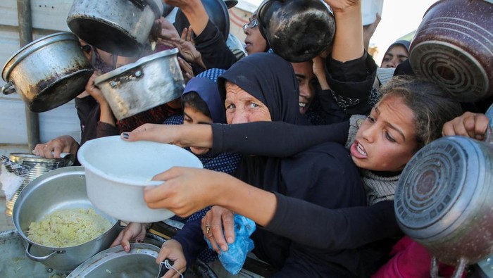 Palestinians gather to receive food cooked by a charity kitchen, amid a hunger crisis, as the Israel-Gaza conflict continues, in Khan Younis in the southern Gaza Strip, November 19, 2024. REUTERS/Hatem Khaled